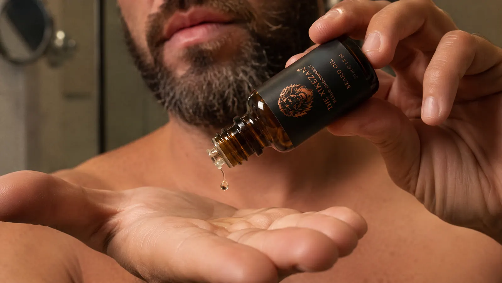 Close-up of a man applying a small amount of beard oil to his palm before working it through his beard