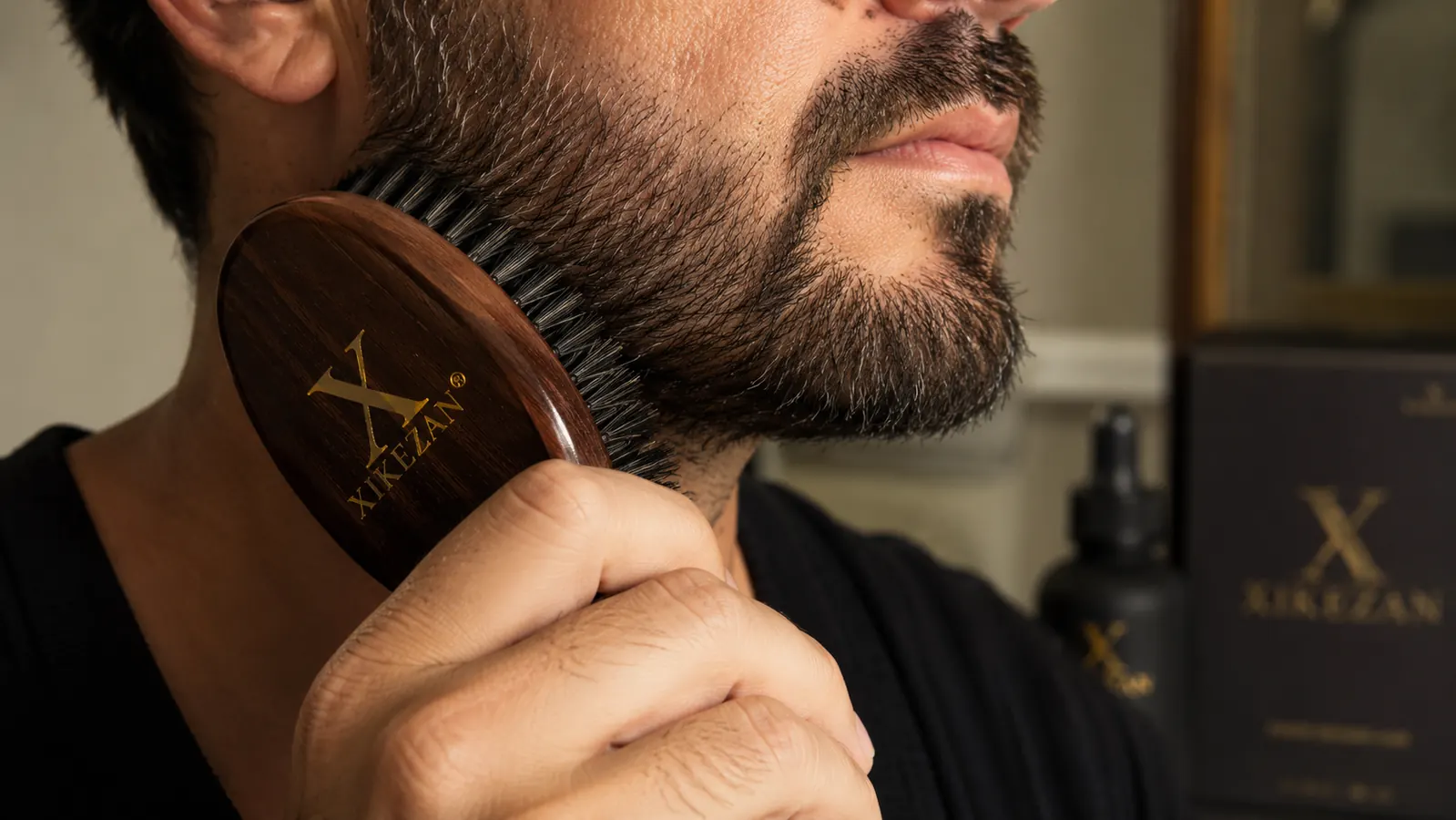 Close-up of a man holding a boar bristle beard brush against a groomed beard