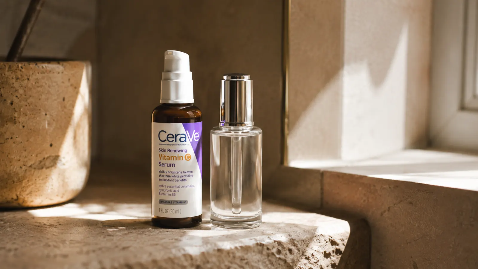 CeraVe Vitamin C Serum bottle standing next to an empty premium luxury serum bottle on a bathroom shelf