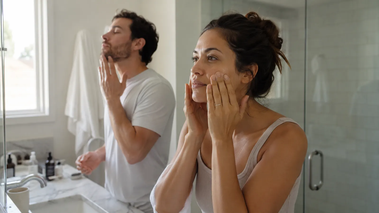 Couple sharing a bathroom mirror during their morning routines