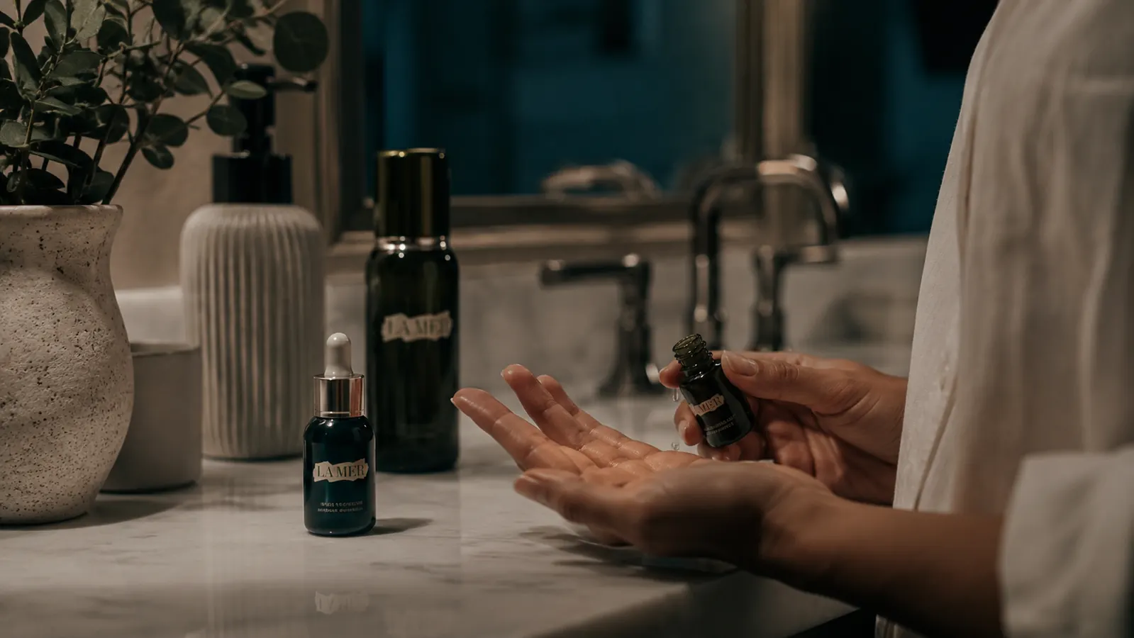 Person applying a few drops of retinol serum to fingertips in a warmly lit bathroom at night