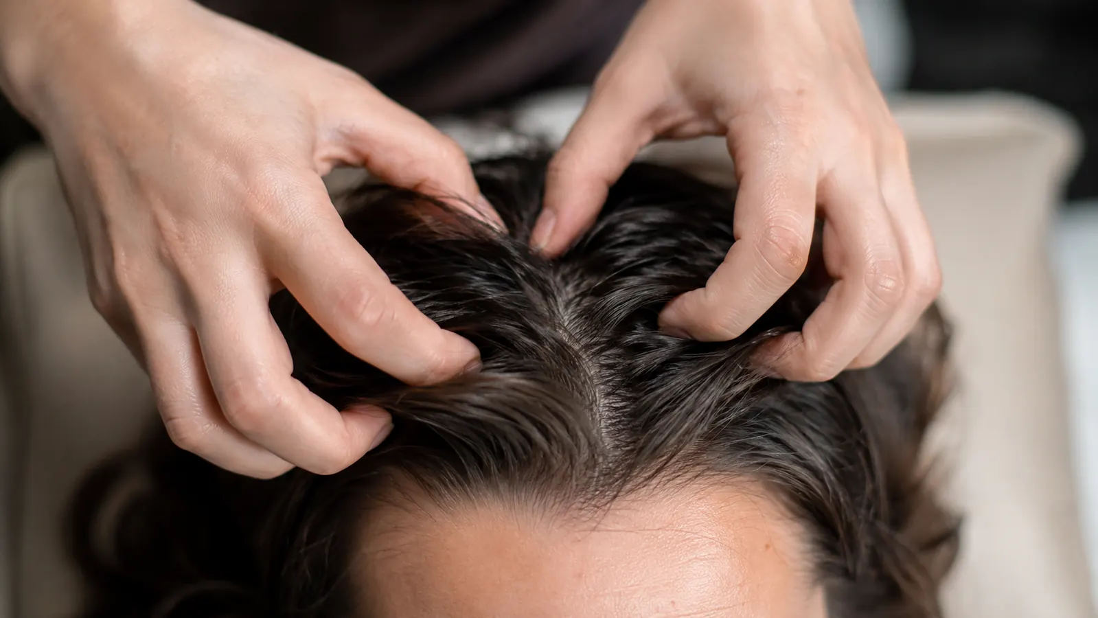 Close-up of fingertip massage technique on scalp showing circular motion