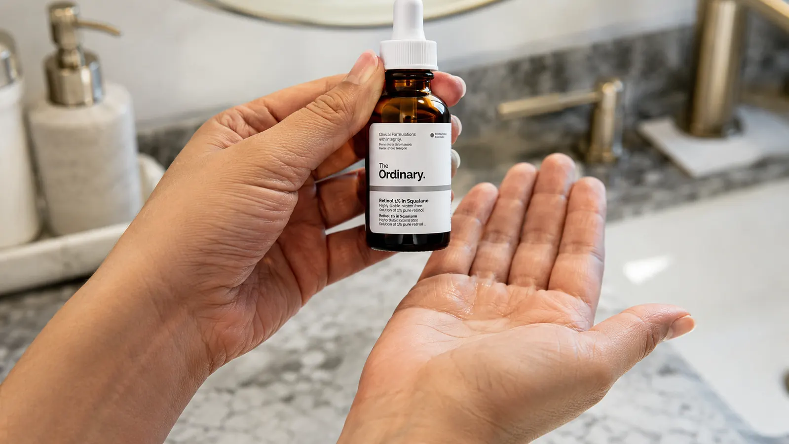 Close-up of hand holding The Ordinary Retinol 1% in Squalane dropper bottle