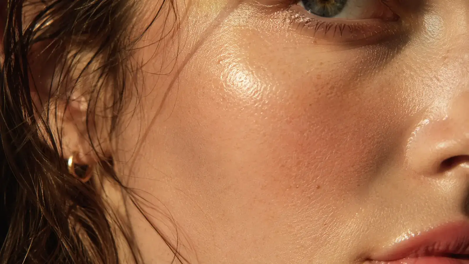 Close-up of a person's cheek showing visibly even, bright skin tone in morning light